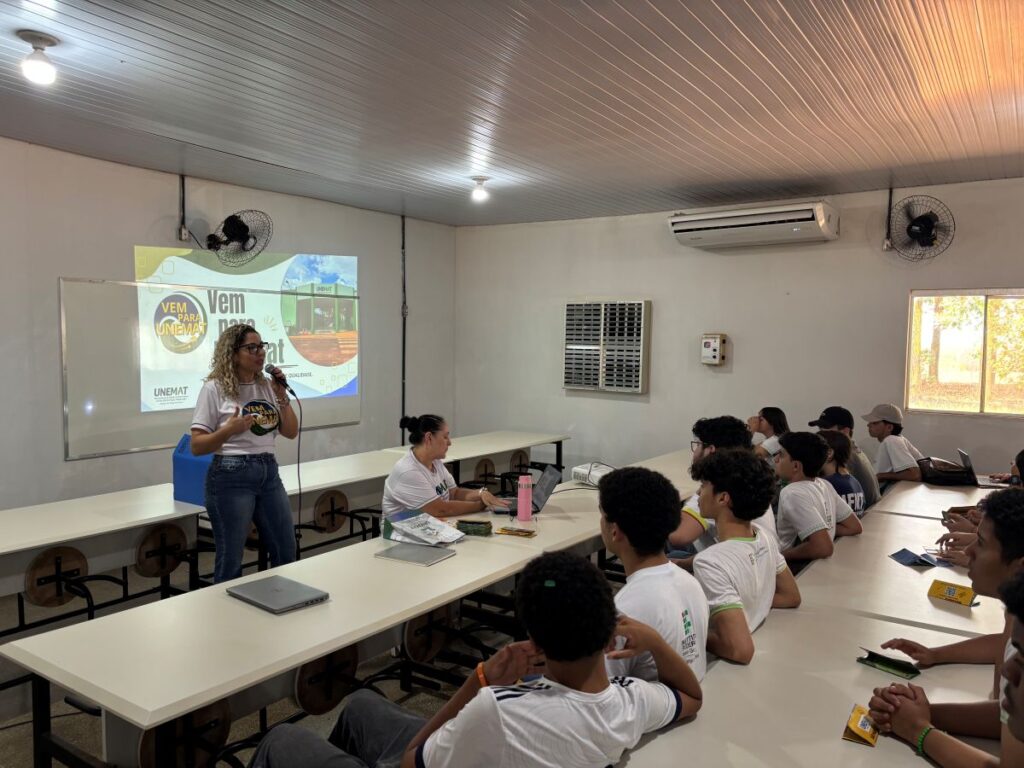 Mulher apresentando cursos da UNEMAT para estudantes do IFMT durante evento no refeitório