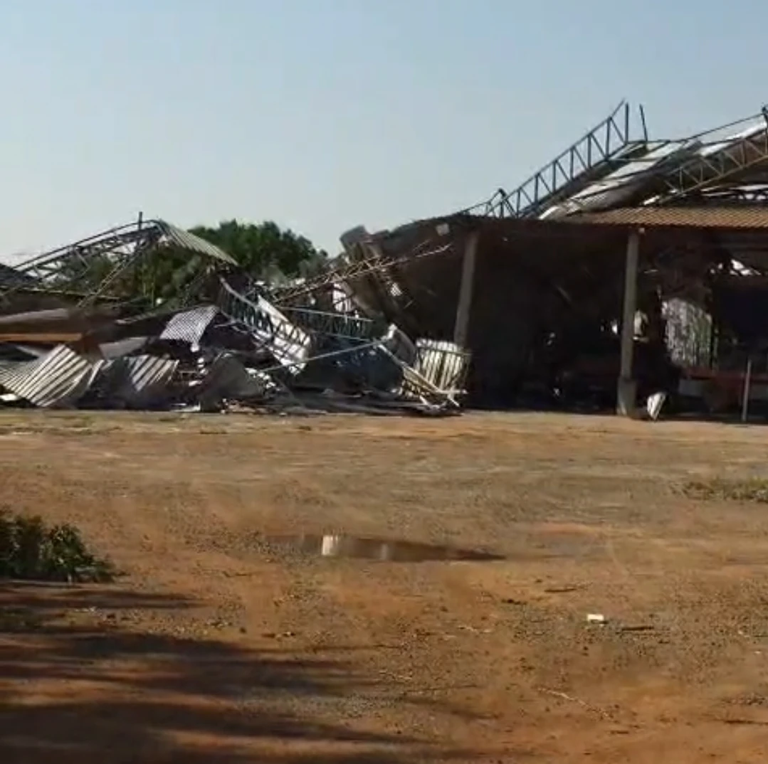 Barracão com telhado e estrutura metálica destruídos, com telhas e ferragens amontoadas, após vendaval em Campo Novo do Parecis