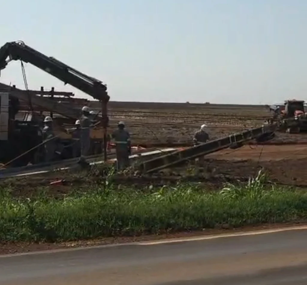 Equipe da Energisa com caminhão guindauto recolhendo poste de concreto caído às margens da BR-364 em Campo Novo do Parecis