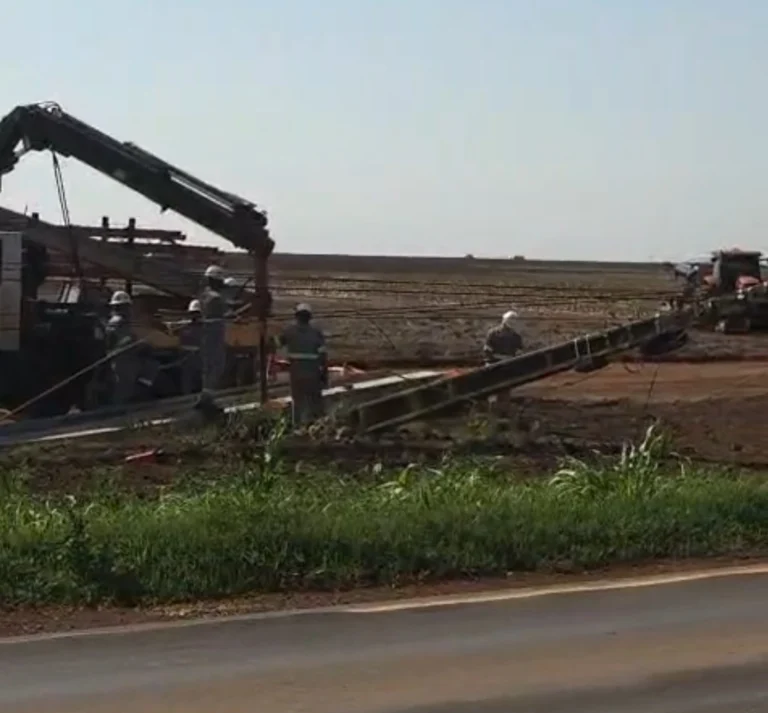 Equipe da Energisa com caminhão guindauto recolhendo poste de concreto caído às margens da BR-364 em Campo Novo do Parecis