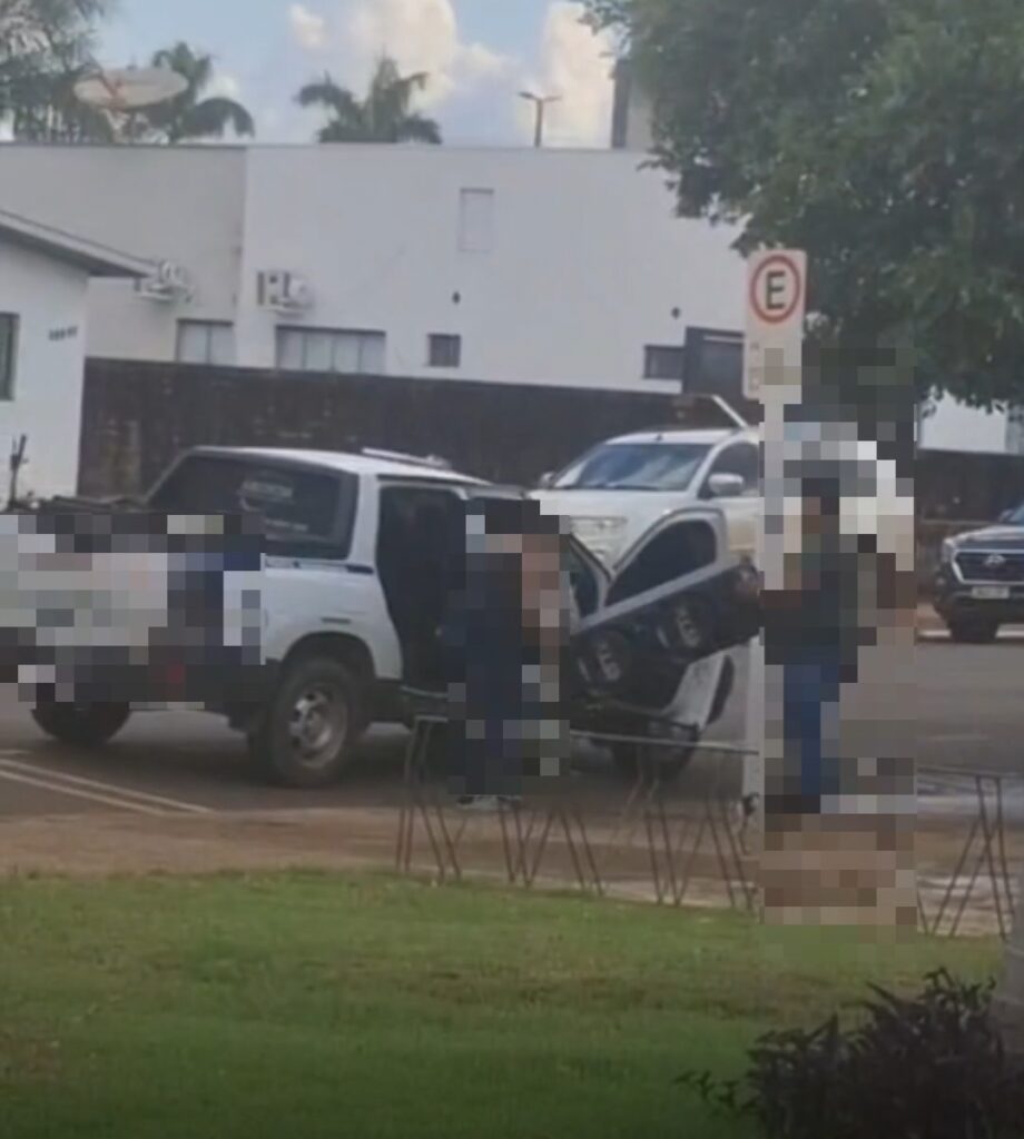 Pessoas com rostos borrados carregam equipamento de som na carroceria de uma caminhonete branca em Campo Novo do Parecis