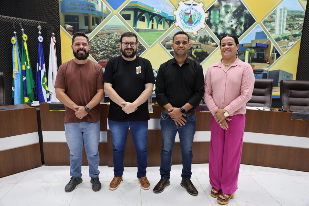Os quatro vereadores eleitos para a Mesa Diretora de 2027, três homens e uma mulher, posam em pé no plenário da Câmara de Campo Novo do Parecis, diante de bandeiras e de um painel com imagens da cidade