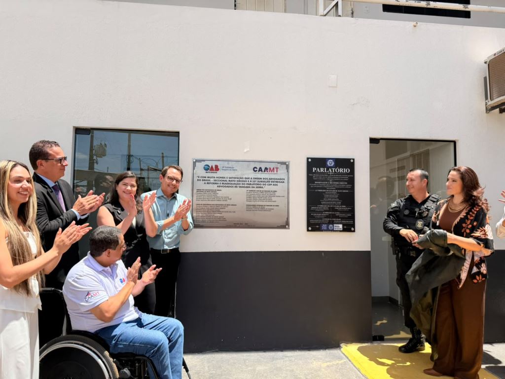 Advogados e dirigentes da OAB aplaudem diante das placas de entrega do parlatório reformado, na entrada do Centro de Detenção Provisória de Tangará da Serra