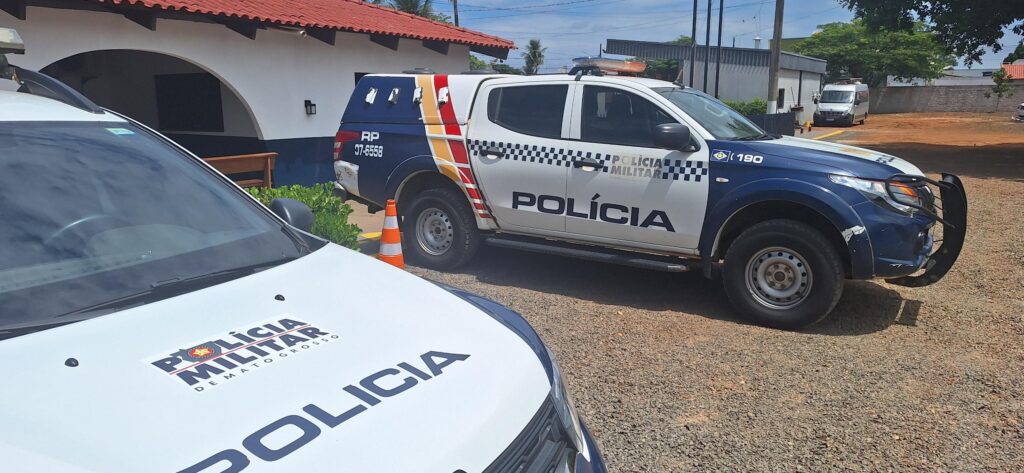 Duas viaturas da Polícia Militar de Mato Grosso estacionadas em frente à sede da 16ª CIPM, em dia de sol