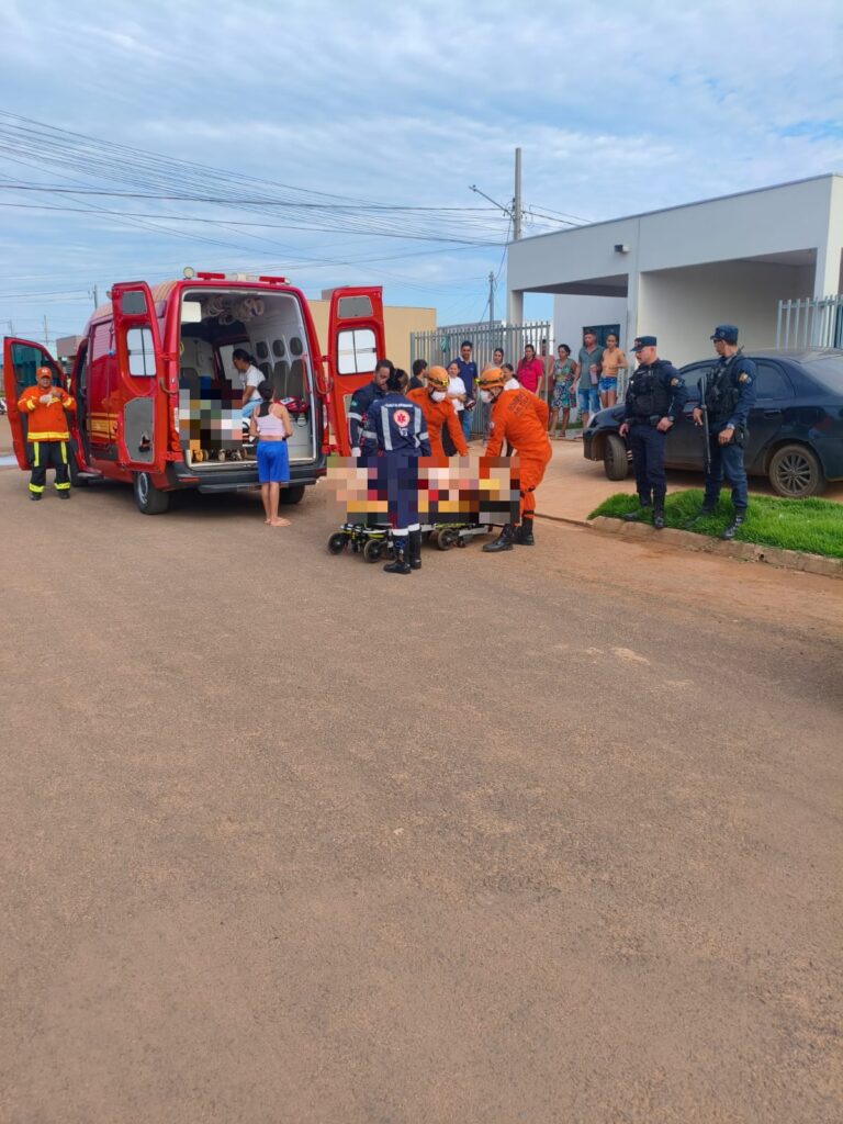 Bombeiros e equipe do Samu atendem vítima em maca na rua, ao lado de ambulância, com policiais militares e moradores observando, no Parque dos Girassóis