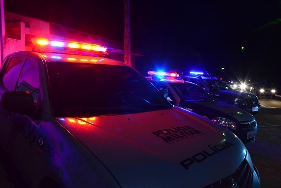 Viaturas da Polícia Militar com giroflex ligado estacionadas em fila durante a noite